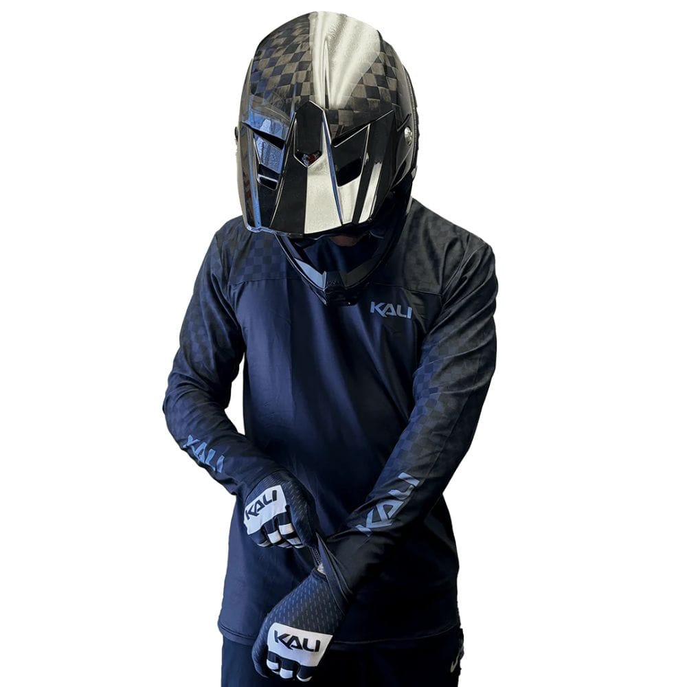 Person wearing a Kali helmet, jacket, and gloves on a white background