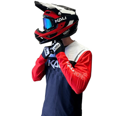 Person wearing a red and black Kali helmet and matching outfit on a white background